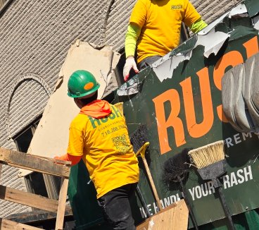 Rush crew in green hard hats loading debris into a Rush container